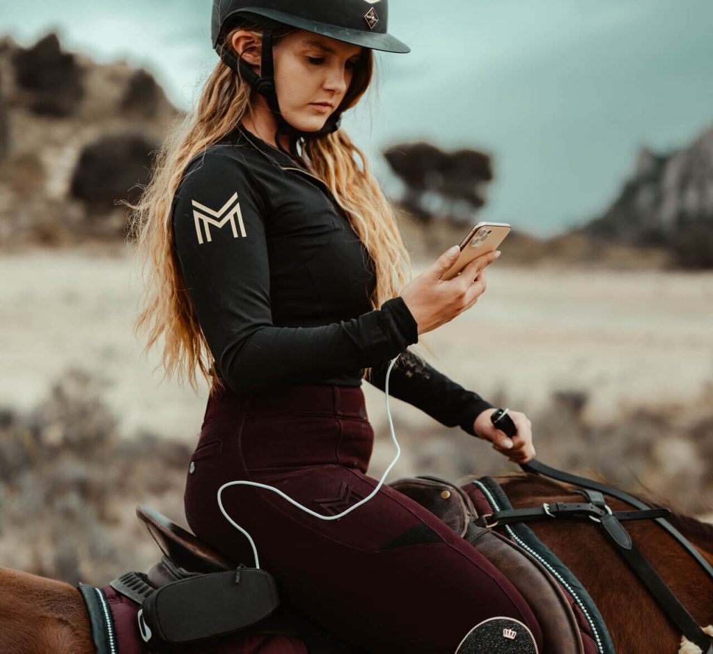 women riding a horse looking at mobile