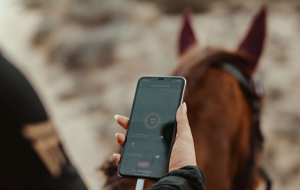 Rider holds a mobile in his hand, he is using the M-GPS Tracker app