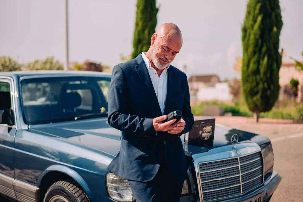 a man infront of his car looking at paj gps tracker