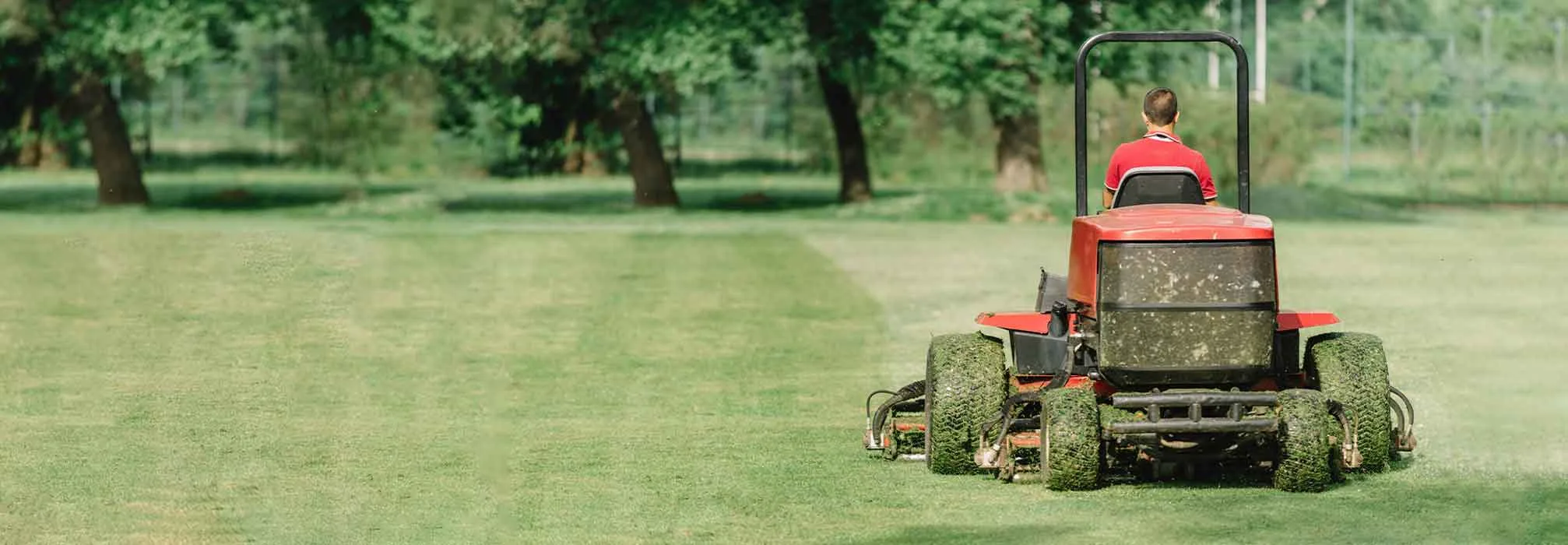 a man mowing grass on a red tractor