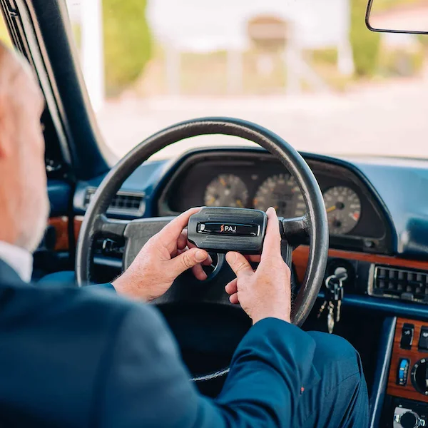 A man holding magnetic gps tracker on steering wheel
